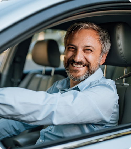 Hombre adulto sonriente manejando su auto